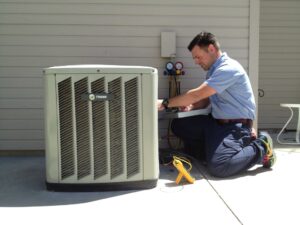Albuquerque HVAC tech kneeling and repairing outdoor HVAC unit.